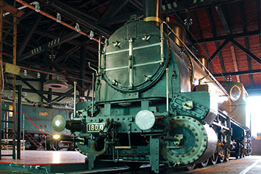 Die Dampflokomotive der Baureihe 180 steht im Rundlokschuppen des SÜDBAHN Museums. Die Lokomotive ist von der Stirnseite zu sehen.